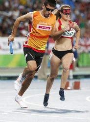 Una corredora junto a su gua, en la prueba de relevos 4x100.