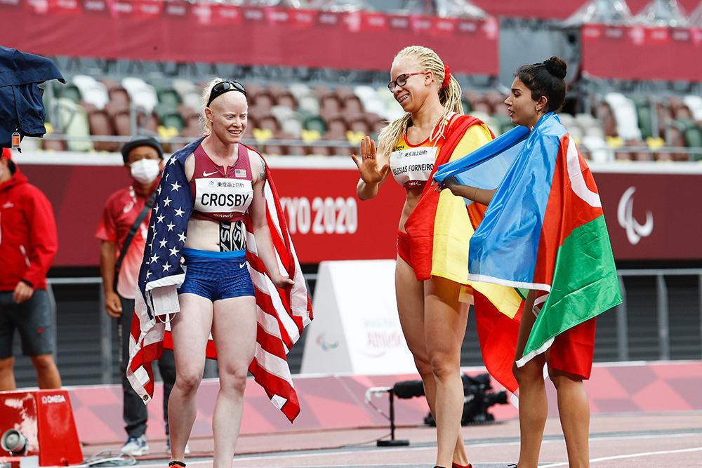 Adieratou Iglesias conversa con las otras dos medallistas sosteniendo sus respectivas banderas nacionales.