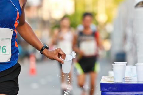 Deportista cogiendo un vaso de agua durante una carrera