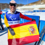 Pol Makuri con la bandera de España tras la prueba clásica de 20km de esquí de fondo JJPP Pekín 2022