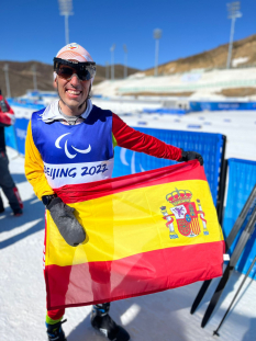 Pol Makuri con la bandera de España tras la prueba clásica de 20km de esquí de fondo JJPP Pekín 2022